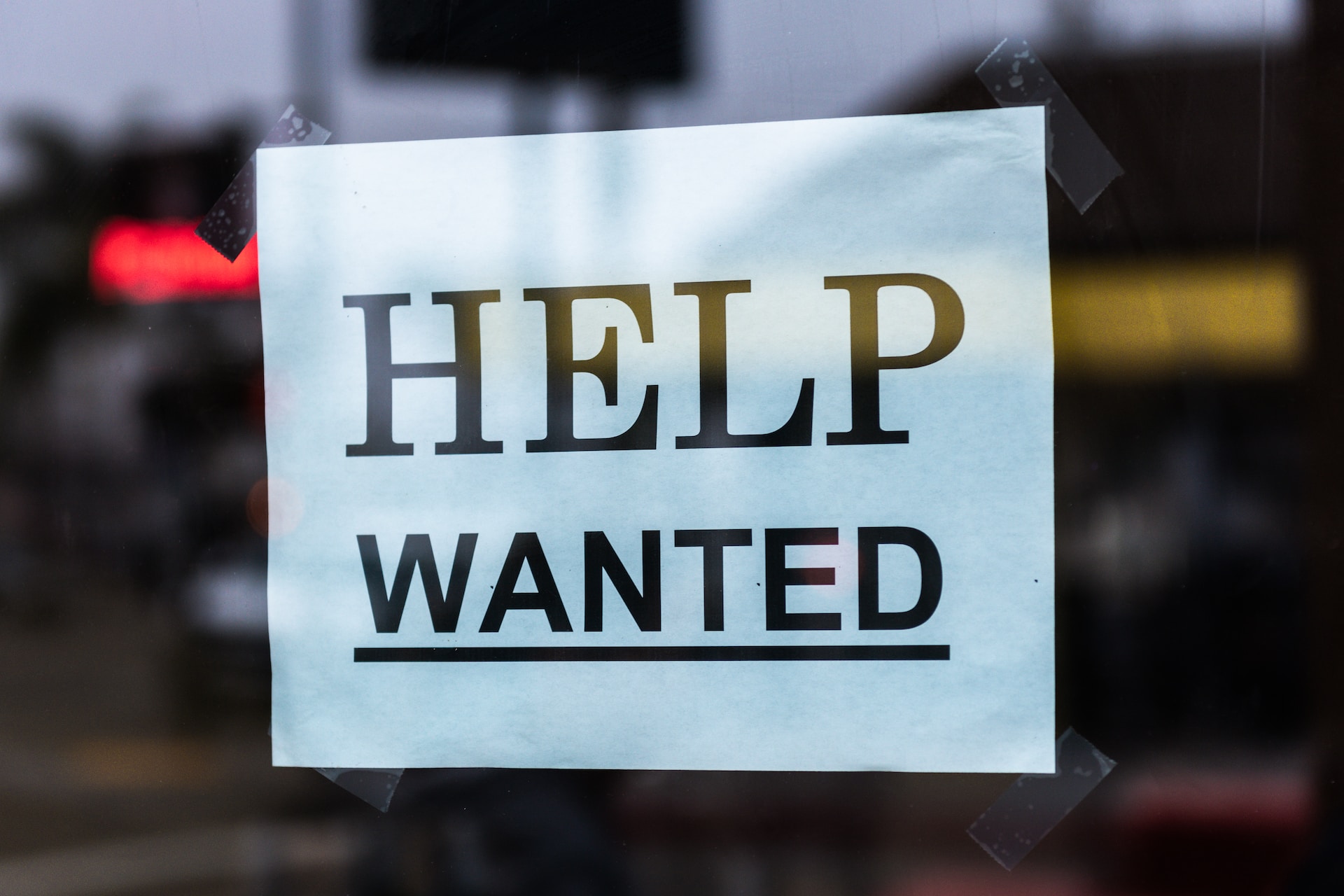 Help Wanted sign taped to a window. Photo by Tim Mossholder on Unsplash.