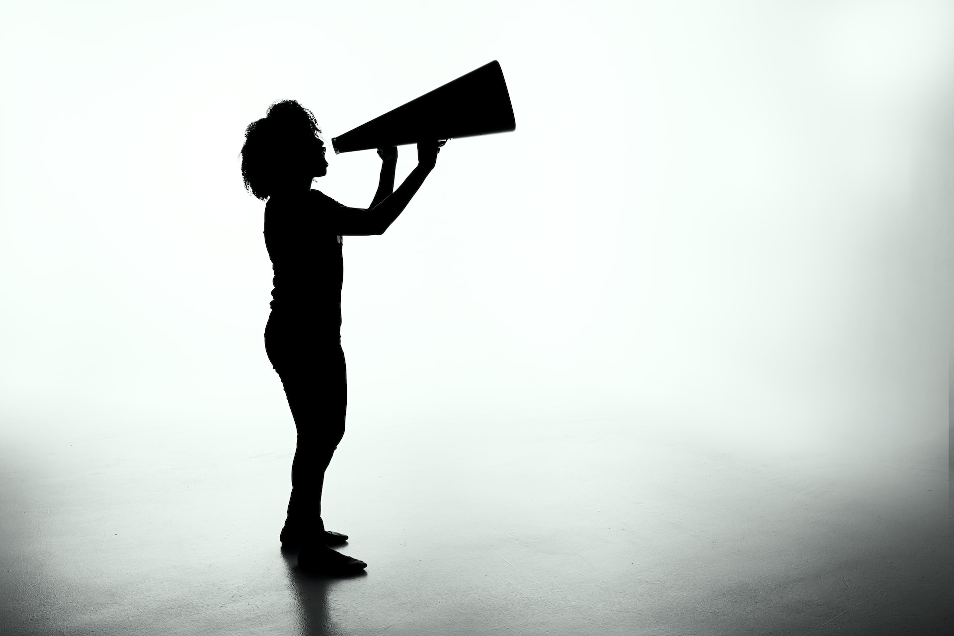 Silhouette of woman shouting into megaphone. Photo by Patrick Fore on Unsplash