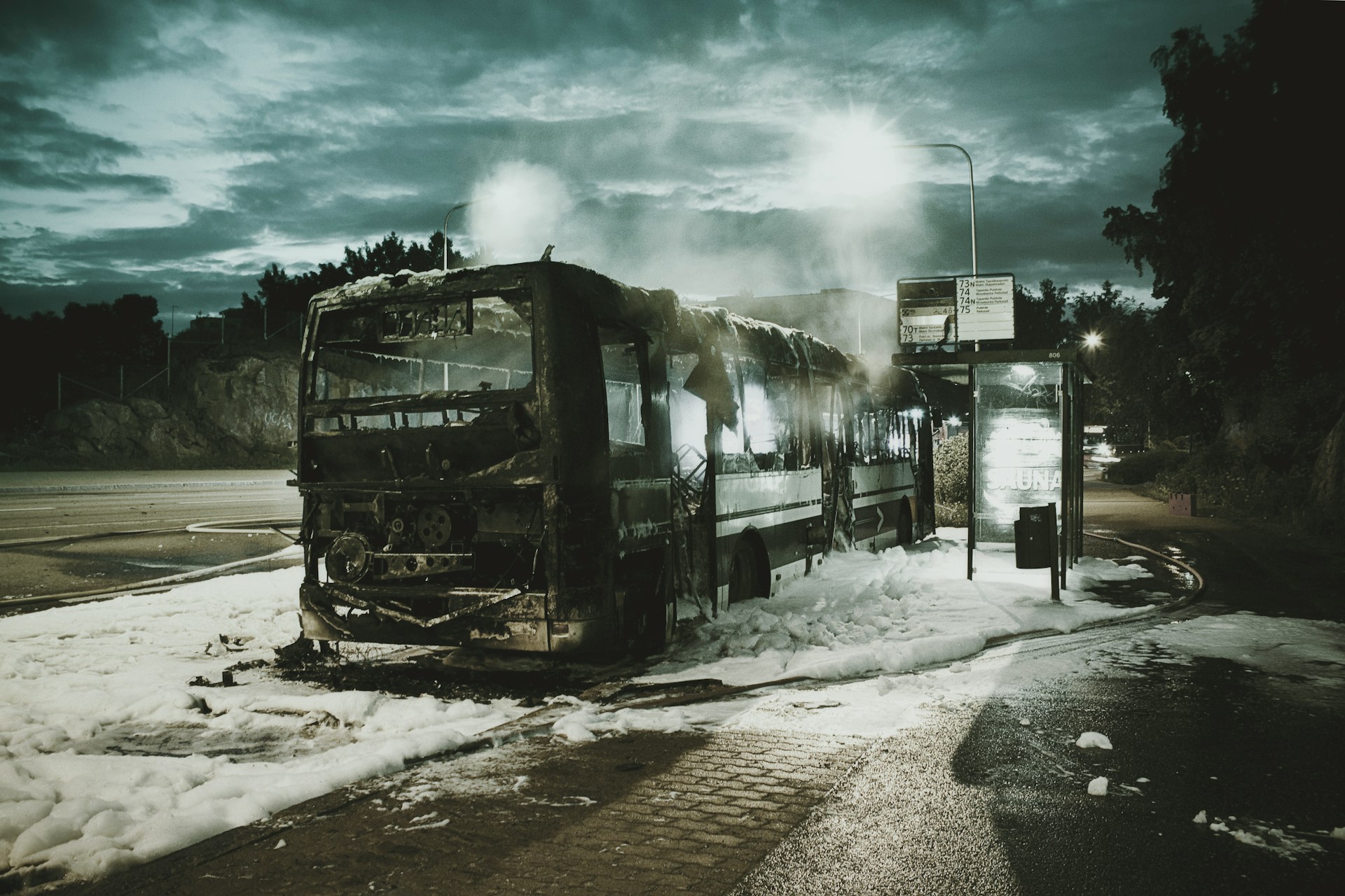 The burned-out hull of a bus, on the side of the road. Photo by Hans Eiskonen on Unsplash.