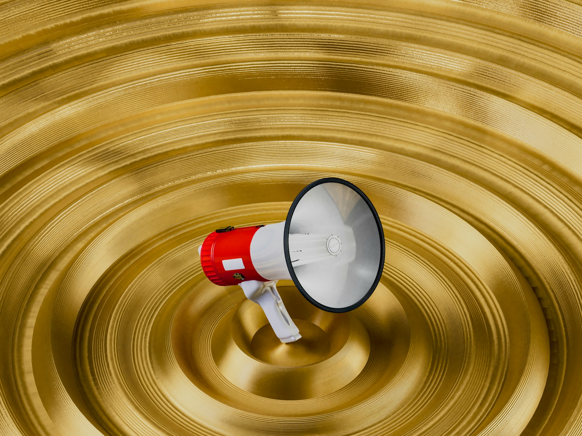 Red and white bullhorn on a gold background.  Photo by Igor Omilaev on Unsplash.