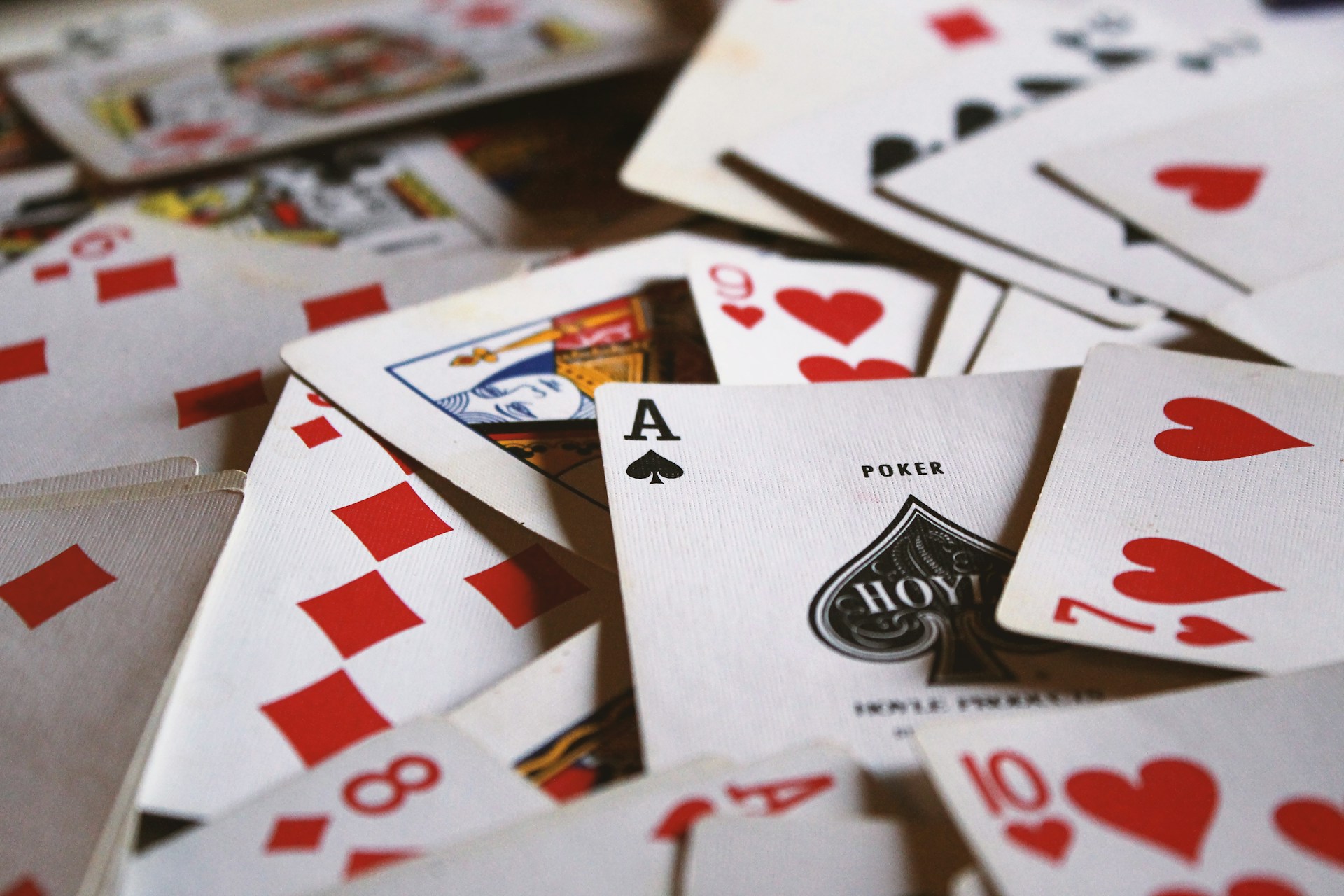 Scattered playing cards. The ace of spades is in the foreground and centered. Photo by Jack Hamilton on Unsplash.