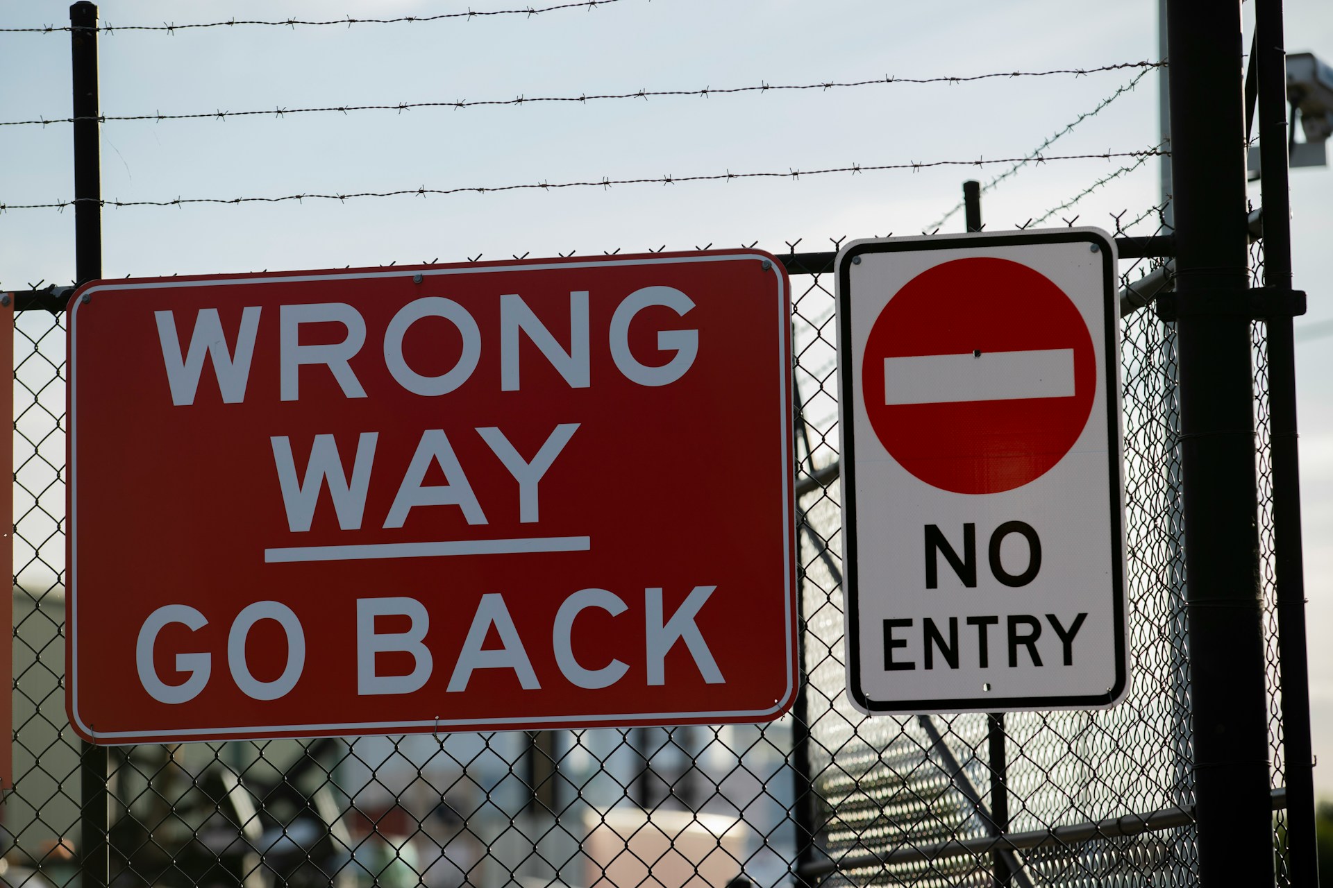 Signs posted on a fence.  One reads 'Wrong Way Go - Back' while the other is 'No Entry' .  Photo by Marcus Reubenstein on Unsplash