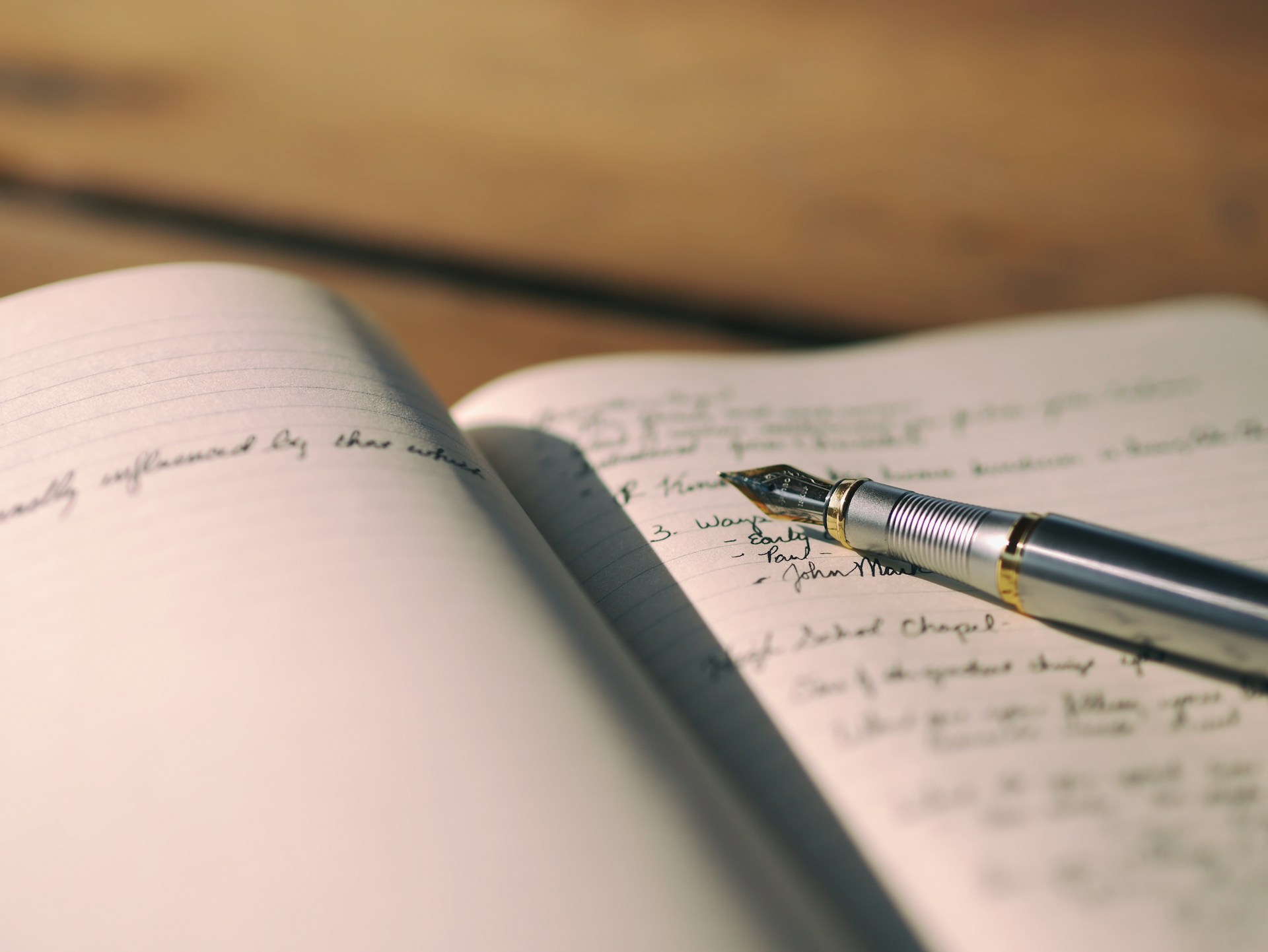 A fountain pen on top of a journal.  Photo by Aaron Burden on Unsplash.