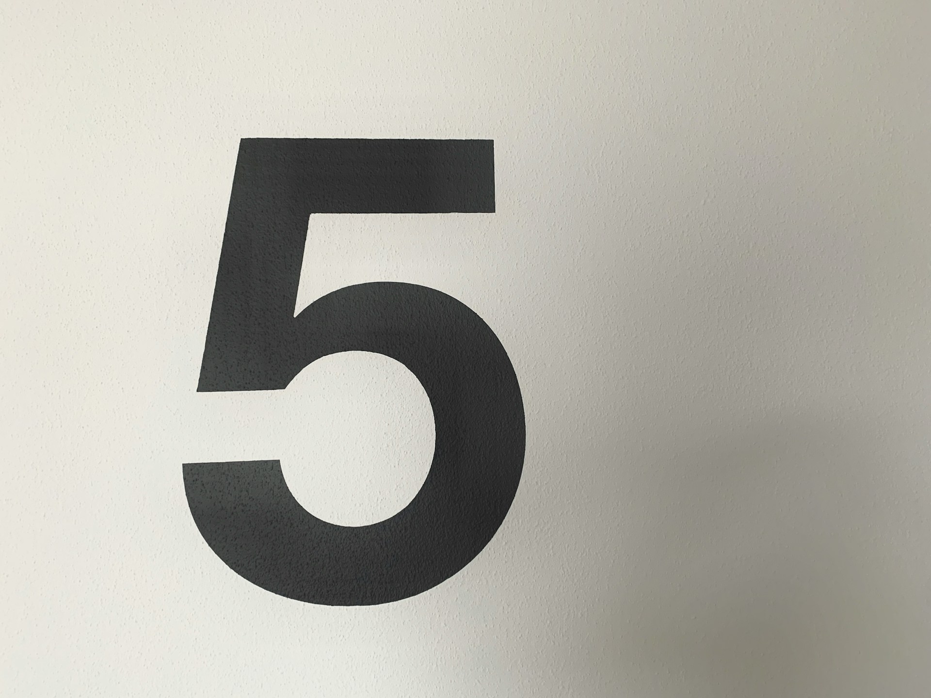 The number five: black text on a white-to-grey gradient background.  Photo by Ralph Hutter on Unsplash.