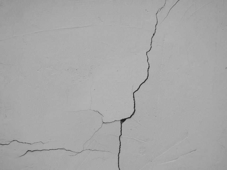 A close-up of cracks on a white wall. Photo by Lallaoke on Unsplash.