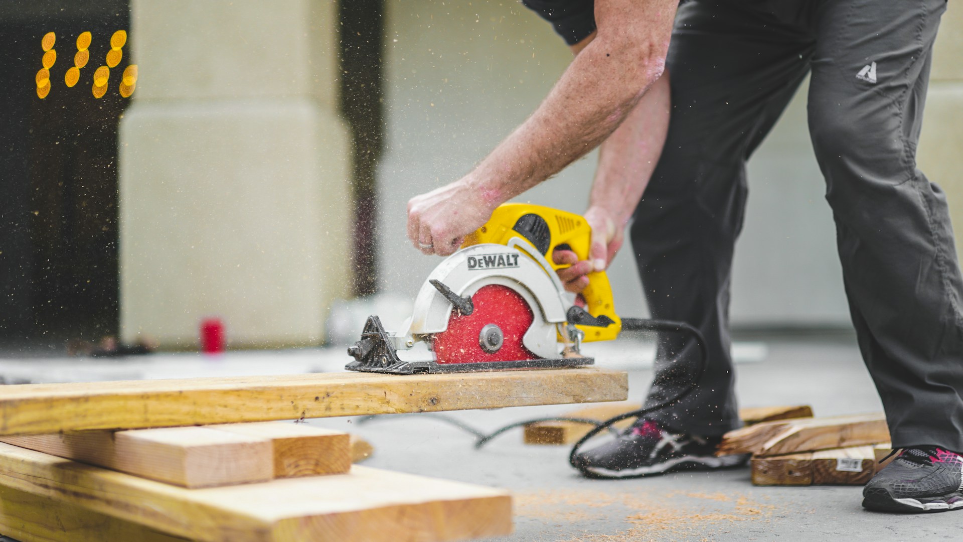 A person cutting through a plank of wood using a circular saw.  Photo by Greyson Joralemon on Unsplash.