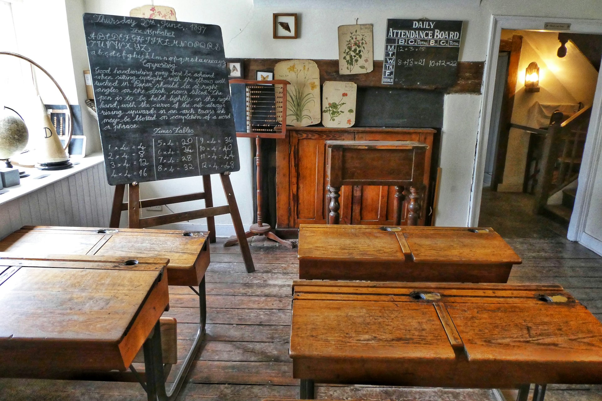 Four wooden desks and a chalkboard, in a setup reminiscent of an old-time classroom.  Photo by Belinda Fewings on Unsplash.