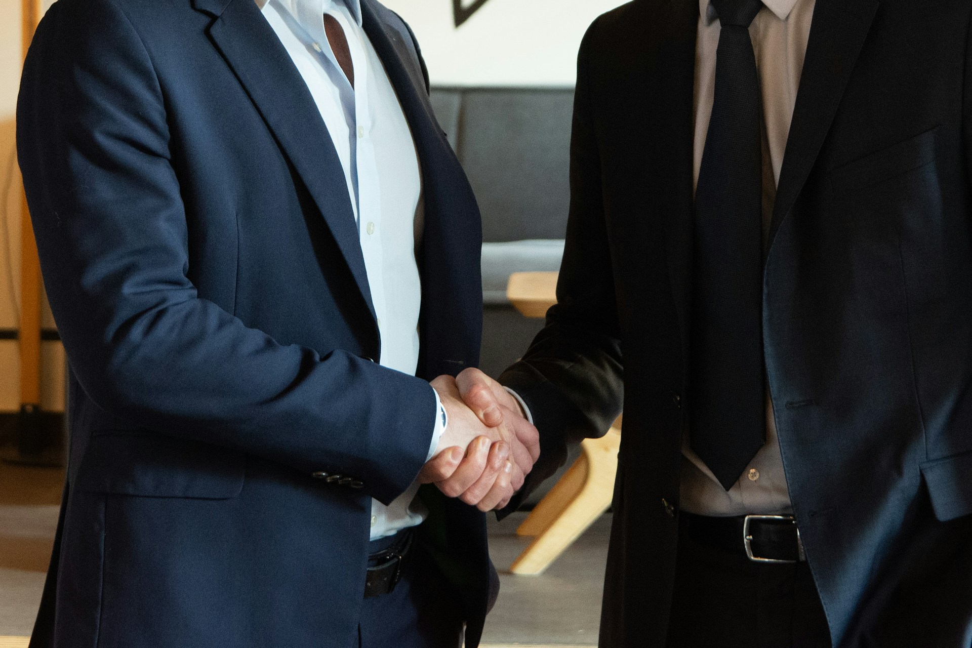 Two people, wearing suits, shaking hands. Photo by Ambre Estève on Unsplash.